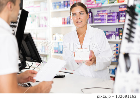 Young female pharmacist serving client buying medicament in drugstore 132691162