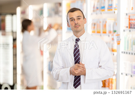 At pharmacy, man apothecary waiting for customers, invite with gesture go to department of cosmetic At pharmacy, man apothecary waiting for customers, invite with gesture go to department of cosmetic 132691167