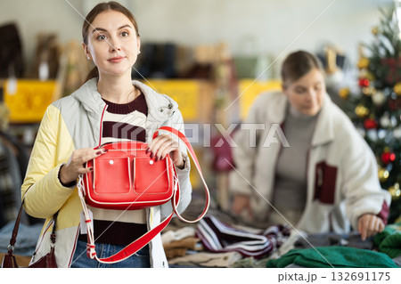 Young woman choosing handbag in clothing store Young woman choosing handbag in clothing store 132691175