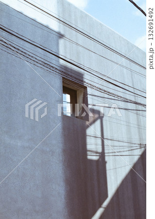 Urban building wall with small window and wire shadows 132691492