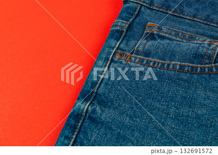 Blue denim jeans on a bright red background in a casual setting 132691572
