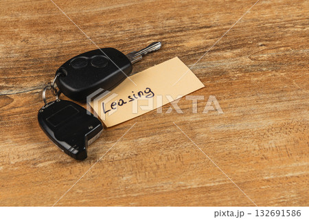 Keys on a wooden table with a note about leasing cars Keys on a wooden table with a note about leasing cars 132691586
