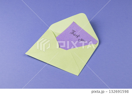 Thank you card inside a light green envelope on a purple background 132691598
