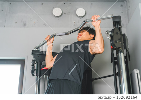 スポーツジムのチンニングマシンで懸垂をする若いアジア人男性 スポーツジムのチンニングマシンで懸垂をする若いアジア人男性 132692164