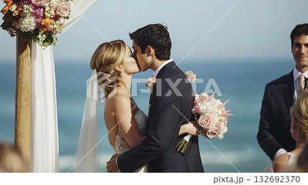 Bride and groom kiss in front of a white arch 132692370
