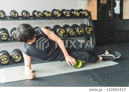 ジムでフォームローラーを使って太ももの筋膜リリースをする男性 ジムでフォームローラーを使って太ももの筋膜リリースをする男性 132692417