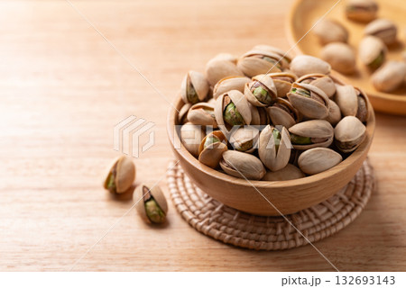 Roasted Pistachio nuts in a bowl on wooden background 132693143