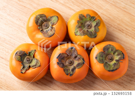 Ripe persimmon fruit on wooden background, Autumn fruit, Top view Ripe persimmon fruit on wooden background, Autumn fruit, Top view 132693158