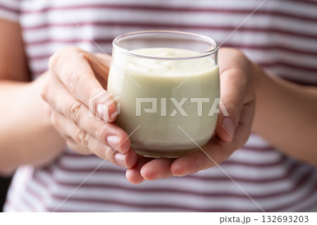 Avocado smoothie with milk in glass holding by woman hand, Healthy drink 132693203