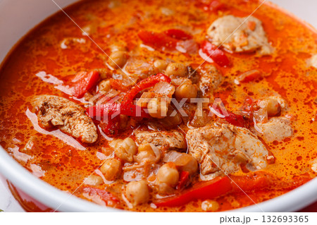 Tikka masala with chicken and chickpeas in red pot. Tikka masala with chicken and chickpeas in red pot. 132693365