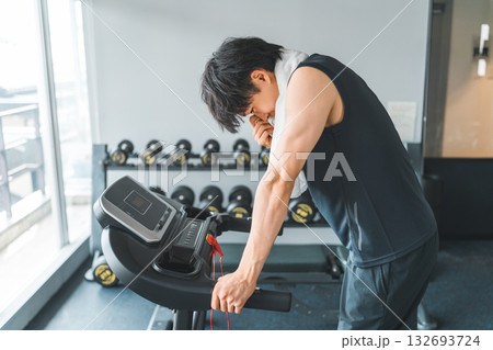スポーツジムのウォーキングマシンで有酸素運動をする若いアジア人男性 スポーツジムのウォーキングマシンで有酸素運動をする若いアジア人男性 132693724