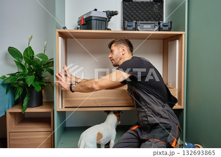 Man assembling wooden furniture cabinet during home renovation Man assembling wooden furniture cabinet during home renovation 132693865