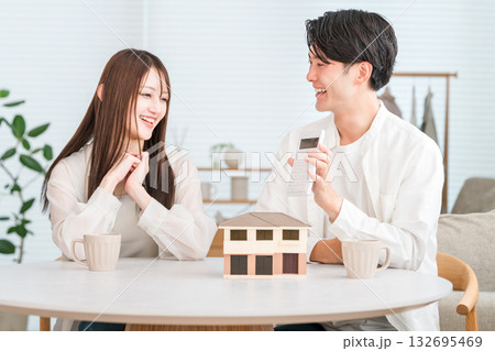 住宅模型を見ながらマイホームの予算を話し合う若いアジア人夫婦 住宅模型を見ながらマイホームの予算を話し合う若いアジア人夫婦 132695469