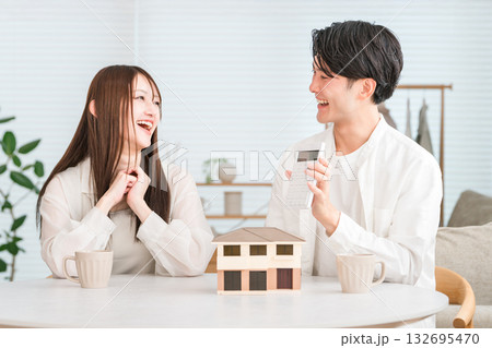 住宅模型を見ながらマイホームの予算を話し合う若いアジア人夫婦 132695470