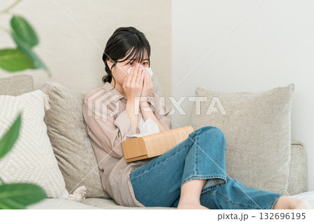 ソファーでテレビや映画を見て涙を拭く若いアジア人女性 ソファーでテレビや映画を見て涙を拭く若いアジア人女性 132696195