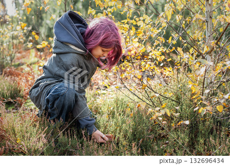 Girl with pink hair foraging mushrooms in autumn forest 132696434