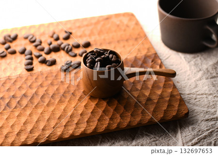 天然木の計量カップに入ったコーヒー豆とコーヒーカップ 132697653