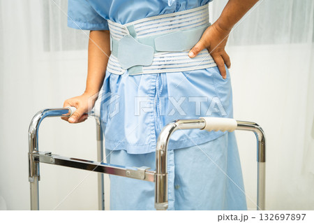 Asian senior pain back wearing elastic support belt with walker. 132697897