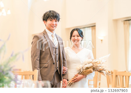 結婚式でチャペル・結婚式場・バージンロードにブーケを持って入場する新郎新婦 結婚式でチャペル・結婚式場・バージンロードにブーケを持って入場する新郎新婦 132697903