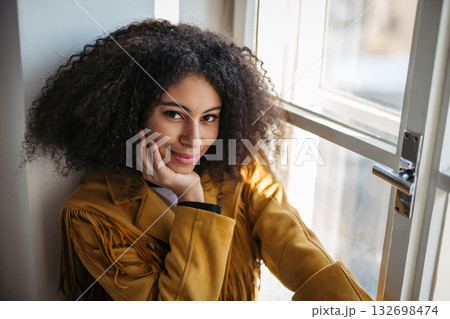 Portrait of beautiful young woman sitting on window sill. Portrait of beautiful young woman sitting on window sill. 132698474