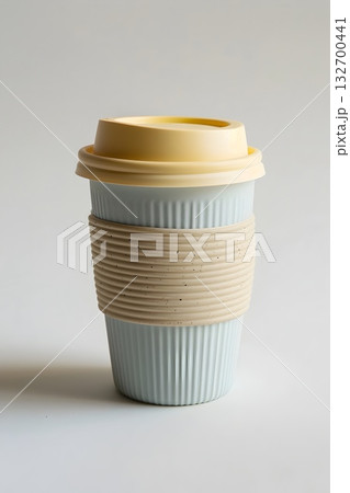 Mint and beige reusable travel mug with ribbed silicone sleeve; minimal studio still life for eco lifestyle. 132700441