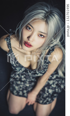 Young woman with silver hair wearing floral dress posing closely in a dimly lit space 132701496