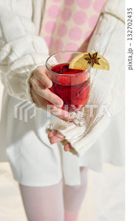 Woman in white outfit and pink scarf holding red drink with lemon slice 132702435