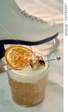 Close-up cocktail with dried orange and marshmallow beside ice skate Close-up cocktail with dried orange and marshmallow beside ice skate 132702447