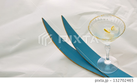 Martini glass with lemon and ice near blue skis on white fabric 132702465