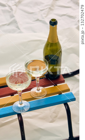 Bottle and two champagne glasses on colorful sledge in winter setting Bottle and two champagne glasses on colorful sledge in winter setting 132702479