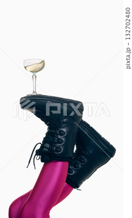 Champagne glass balanced on ski boots with pink leggings on white background 132702480