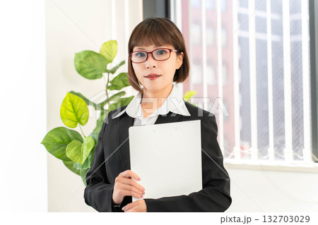 バインダーを手にするメガネをかけた女性 132703029