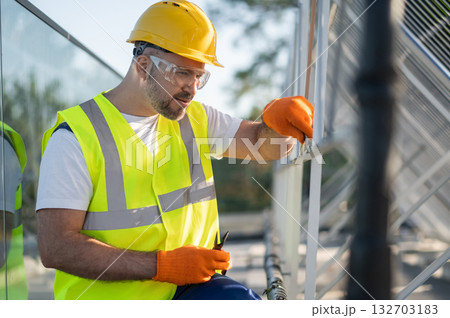 Technician working on rooftop installing and inspecting solar panels 132703183
