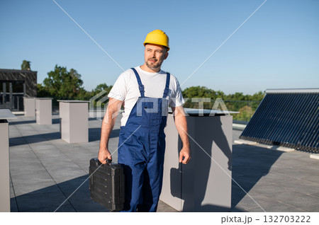 Worker standing with toolbox near photovoltaic solar installation Worker standing with toolbox near photovoltaic solar installation 132703222