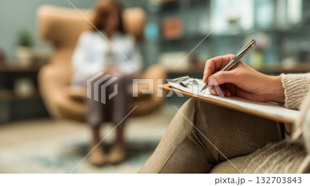 Taking notes during a therapy session in a calm setting with a focused participant Taking notes during a therapy session in a calm setting with a focused participant 132703843
