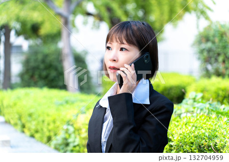 外出先で電話対応をするスーツの女性 132704959
