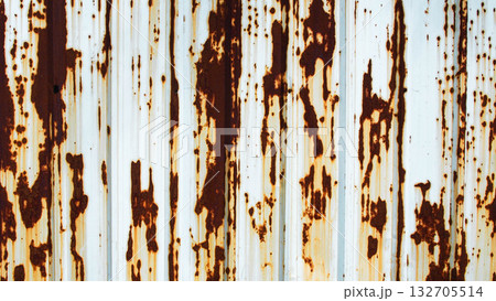 Close-up texture of rusty metal sheet with brown corrosion stains on a white painted surface. Grunge industrial background showing natural oxidation and aging metal patterns. 132705514