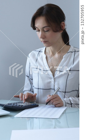 Female professional calculating finances, reviewing paperwork, tracking business expenses with precision and focus. Audit and taxes in business Female professional calculating finances, reviewing paperwork, tracking business expenses with precision and focus. Audit and taxes in business 132705955