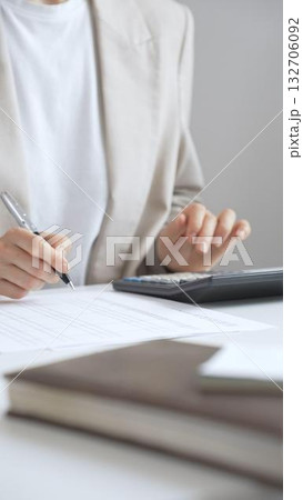 Businesswoman is calculating annual tax using calculator and taking notes in the office, managing domestic budget and checking financial documents. Audit and taxes in business Businesswoman is calculating annual tax using calculator and taking notes in the office, managing domestic budget and checking financial documents. Audit and taxes in business 132706092