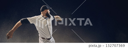 Baseball pitcher winding up before throw with dust particles floating in dramatic light. Banner Baseball pitcher winding up before throw with dust particles floating in dramatic light. Banner 132707369