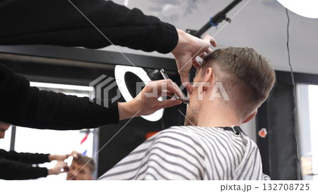 Skilled barber performing precise hair fade using straight razor, working on client's hair in contemporary grooming salon with professional tools Skilled barber performing precise hair fade using straight razor, working on client's hair in contemporary grooming salon with professional tools 132708725