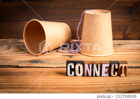 Two paper cups linked by string next to colorful wooden blocks spelling CONNECT Two paper cups linked by string next to colorful wooden blocks spelling CONNECT 132708930