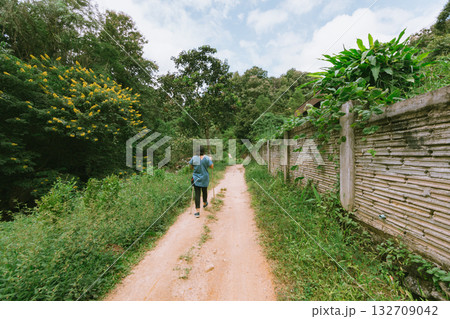 Back view of young female traveler with trekking sticks 132709042