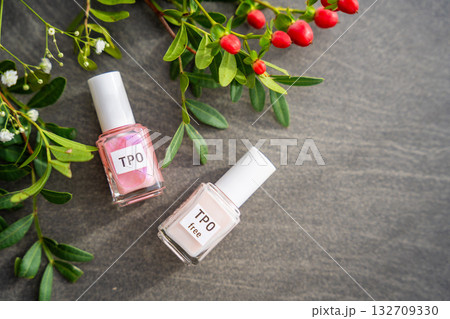 Two gel nail polish bottles labeled TPO and TPO Free on a table with flowers. Concept of chemical awareness and safe beauty products without Trimethylbenzoyl Diphenylphosphine Oxide 132709330