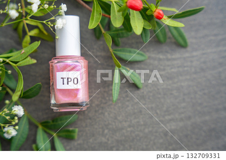 Pink gel nail polish bottle labeled TPO held in hand. Focus on harmful ingredient Trimethylbenzoyl Diphenylphosphine Oxide in beauty products. 132709331