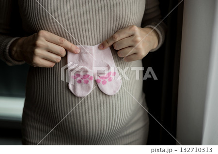 Pregnant woman holding baby socks on belly 132710313
