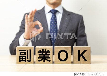 「副業OK」と書かれたブロックとOKポーズをするビジネスマン 132711402