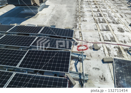Broken down photovoltaic solar panels destroyed by hurricane Ian winds mounted on industrial building roof for producing green ecological electricity. Consequences of natural disaster 132711454