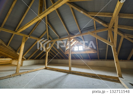 Attic of a building with wooden beams of a roof structure and a small window. Attic of a building with wooden beams of a roof structure and a small window. 132711548