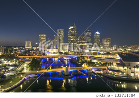 American city skyline with brightly illuminated high commercial buildings and bridge over Hillsborough river. Night urban landscape of downtown district of Tampa in Florida, USA. 132711584